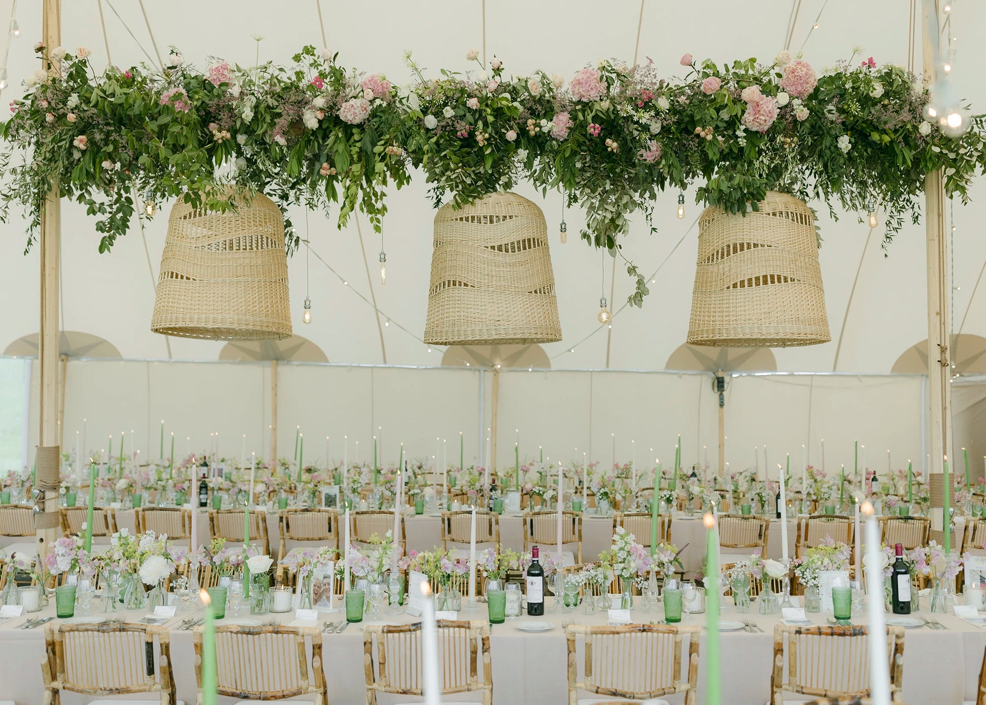 Decorative setup with hanging floral arrangements and wicker lanterns over a table.